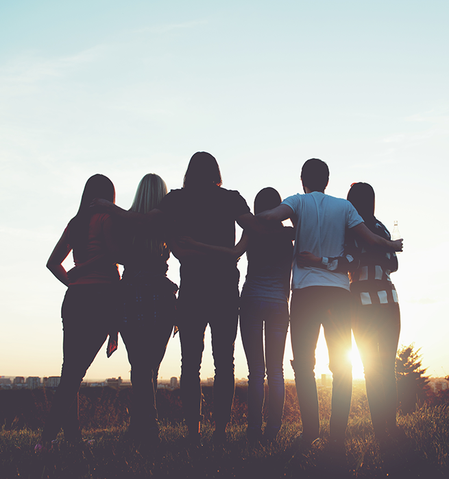 group of people in addiction recovery with their arms around each other outdoors