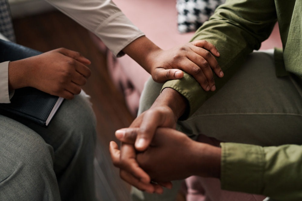 addiction therapist placing hand on patients arm in support