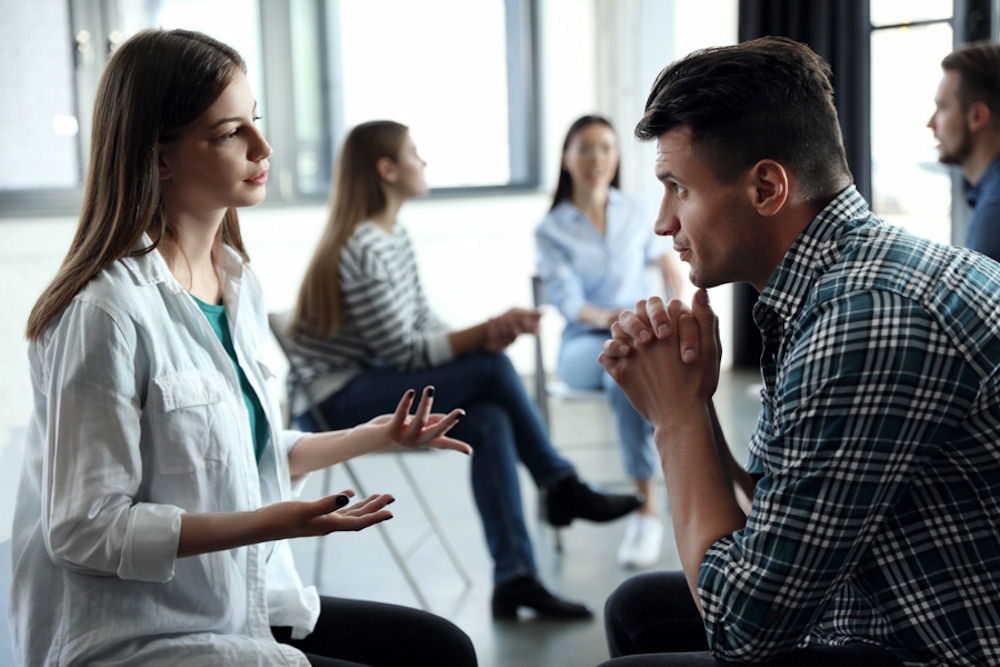 man and woman having a discussion in support group