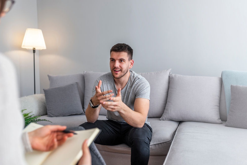 man sitting on a couch talking to a counselor