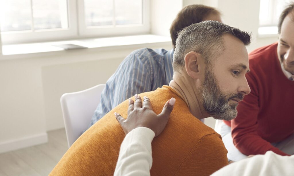 man receiving support in group therapy