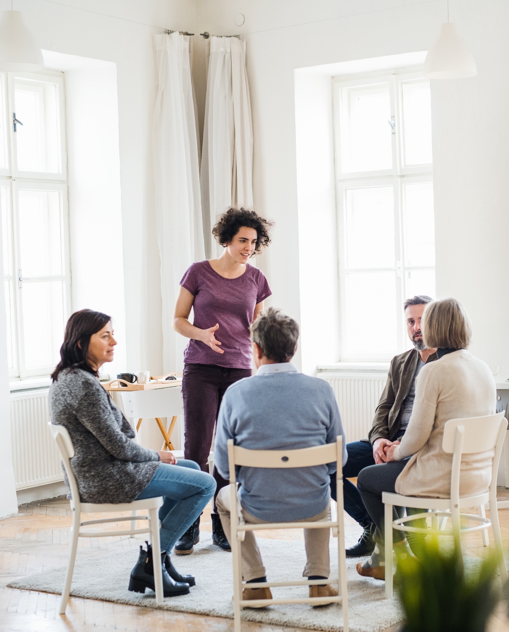 A young woman standing and talking to other people during group therapy. group therapy in colorado for addiction